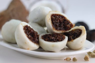 Buharda pişirilmiş pirinç köftesi, içi palmiye jölesi ve taze rendelenmiş hindistan cevizi. Kerala 'nın popüler yemekleri genelde Kozhikatta olarak bilinir. Beyaz arka planda avuç içi tırtıklı ve hindistan cevizli bir fotoğraf.