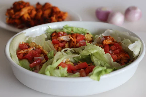 Lettuce chicken wrap. Tandoori chicken bites, sauteed baby corn, fresh cut tomatoes and onions tossed and wrapped in iceberg lettuce leaves. Shot on white background