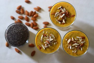 Dilimlenmiş bademlerle süslenmiş alphonso mango ve chia tohumlu milkshake. Beyaz arkaplanda çekilen