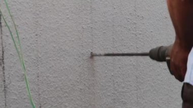 Ağır bir elektrikli matkap kullanarak beton bir duvara delik açmak.