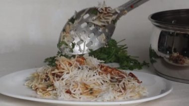 Biryani peyniri ya da Biryani peynirini çelik biryani kabından bir tabağa servis etmek. Haşlanmış ve baharatlı basmati. Krem rengi süzme peynir soslu pirinç. 