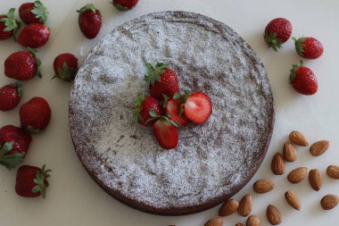 Torta caprese. Chocolate and almond cake. A yummy chocolaty flourless cake from the Capri island of Italy. Sprinkled with sugar powder and shot along with fresh strawberries on white background.