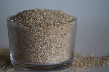 Kırık buğday, nuruku gotahambu ya da Dalia. Kahvaltılık güveç için zengin bir lif. Buğday çeşitleri. Bardakta duruyordu. Beyaz arkaplanda çekilen