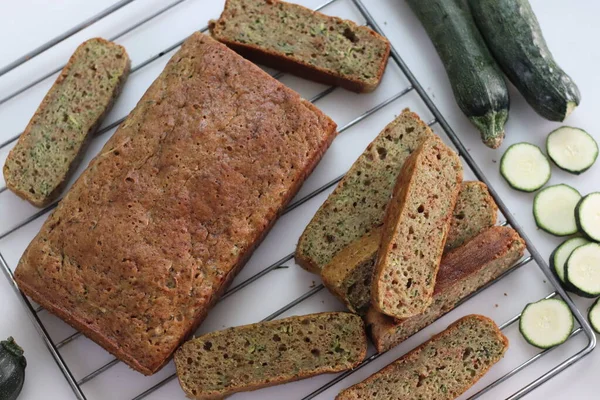 Whole wheat zucchini bread slices. Moist and dense bread made of whole wheat flour and shredded zucchini. A healthy breakfast option. Shot with baking grill below on a white background