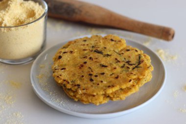 Makki ki roti veya Maize roti. Mısır unundan yapılmış mayasız bir Hint ekmeği. Bir bardak mısır unuyla birlikte beyaz arka planda çekilmiş.