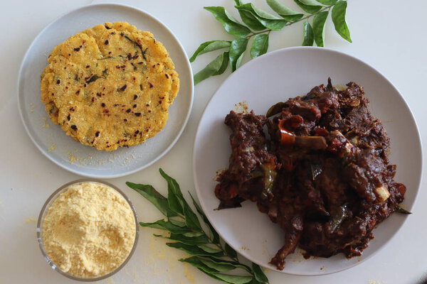 Mutton roast served with Makki ki roti or Maize roti. Spicy mutton roast prepared in Kerala style served with Indian flat unleavened bread made from corn meal flour. Shot on white background