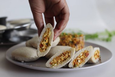 Paneer doldurulmuş kodo darı. Kodo millet ve mercimek unundan yapılmış buğulanmış tuzlu kekler soğan ve domatesli çırpılmış süzme peynirle doldurulmuş. Beyaz arkaplanda çekilen