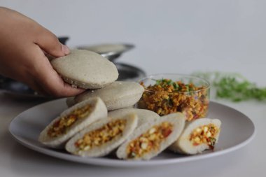 Paneer doldurulmuş kodo darı. Kodo millet ve mercimek unundan yapılmış buğulanmış tuzlu kekler soğan ve domatesli çırpılmış süzme peynirle doldurulmuş. Beyaz arkaplanda çekilen