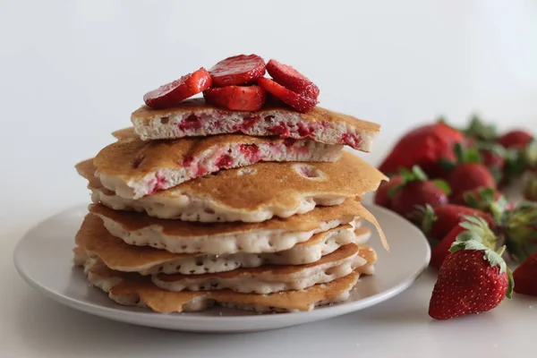 Strawberry pancakes. Soft and fluffy Buttermilk pancakes with fresh strawberries made with fresh cut strawberries added to the batter made of flour, buttermilk and eggs. Shot on white background