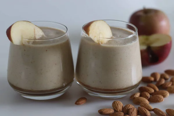 Apple milk shake. Summer drink milkshake made of almond milk and frozen apples. Shot on white background with apple and almonds.