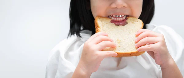閉鎖だ 子供の手はパンを保持し 子供の歯はガストでパンのローフに噛むビットです — ストック写真