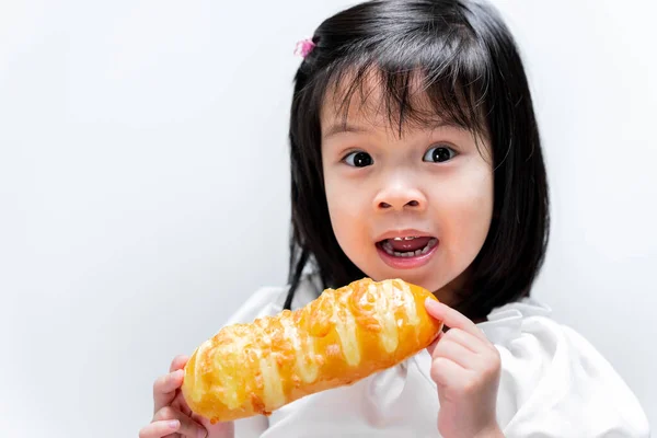 美しい少女自宅で甘いパンを食べている 子供たちはパン屋を食べてうれしいです 白の背景 — ストック写真