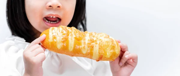 閉めろ 黄色いパンを持っている子供の手 パンの後ろで 子供たちは甘いパン屋に噛みつくために口を開けています — ストック写真
