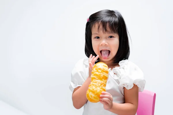 幸せな子供は彼女の舌を突き出す 子供はパンを食べる 子供たちは指で甘いクリームを吸う 白地に — ストック写真