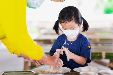 Çiftçi bir anaokuluna tuz ve su ile karıştırılmış tuzlu yumurta yapmayı öğretiyor. Yüz maskesi takan insanlar toz kirliliğini önlüyor PM2.5 ve coronavirus covid19.