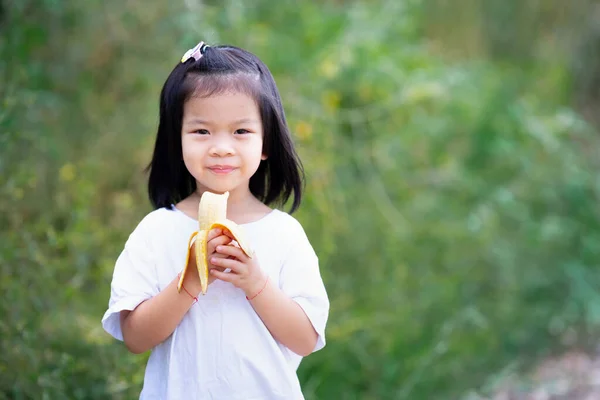 Gadis Asia Senyum Manis Anak Itu Memegang Pisang Kuning Tangannya — Stok Foto