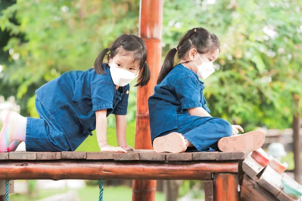 Δύο Κορίτσια Άσπρη Μάσκα Παίζουν Αναρρίχηση Ξύλινο Εξοπλισμό Παιδικής Χαράς — Φωτογραφία Αρχείου