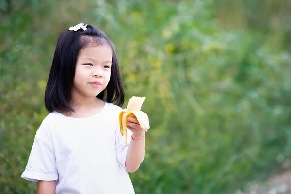 Ένα Κοριτσάκι Που Κρατάει Κίτρινη Ώριμη Μπανάνα Στο Χέρι Της — Φωτογραφία Αρχείου