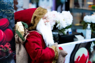 Noel Baba figürü nazik bir gülümsemeyle duruyor, gözlük takıyor. Uzayı kopyala Mutlu Noeller..