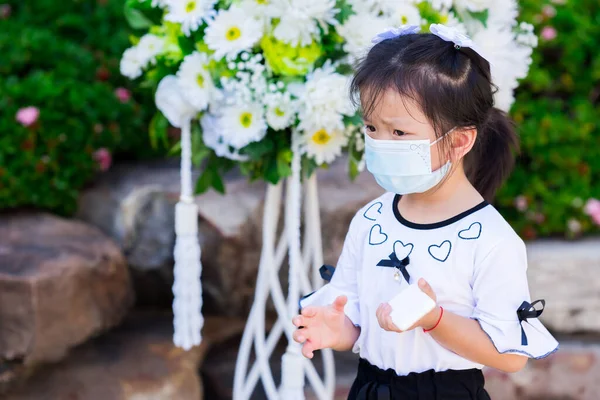 Portre çocuğu 5 yaşında, maske takıyor. Elinde alkol spreyi tutan bir çocuk. Çocuklar kaşlarını çattı. Beyaz ve siyah tişörtlü kız. Boş boşluk.