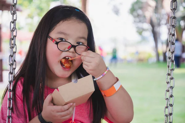 子供の肖像画5 かわいいアジアの女の子は紙皿から軽食を食べています 子供はスイングに座っている 子供は近視のため眼鏡をかける 夏のアクティビティ テキストを入力するための空のスペース — ストック写真