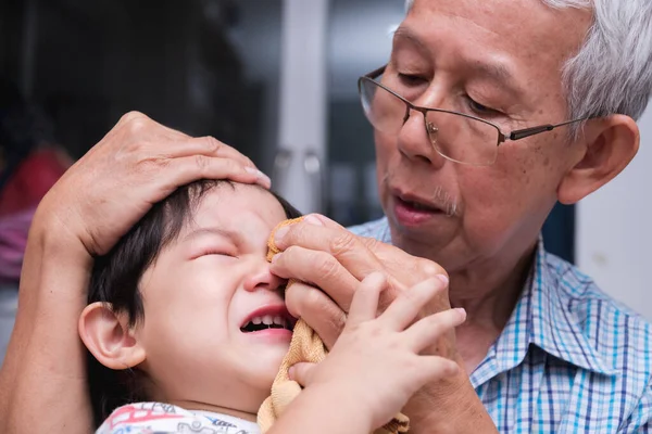 Portrait image family. Father comforting son who is crying heavily due to forehead injury. Adult man helping to apply ice wrapped in towel to swollen forehead. Basic first aid. Embrace and comfort.