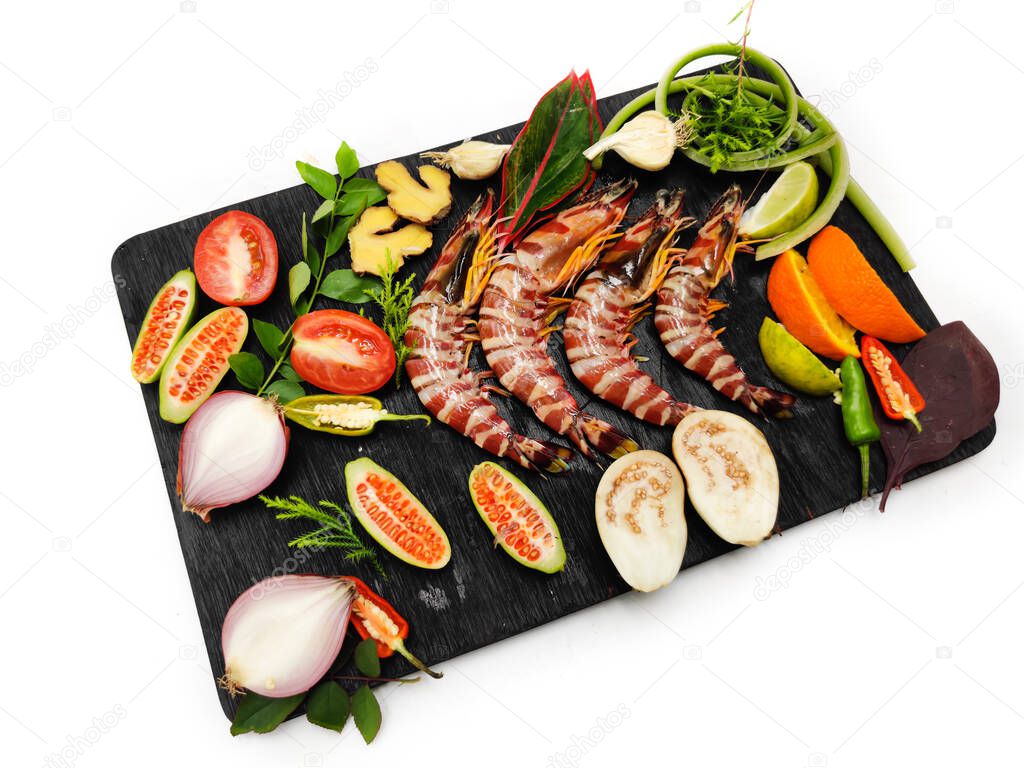Fresh Tiger Shrimp decorated with spices and herbs on a wooden pad.Isolated on white background.