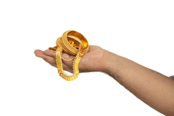 Pahalı altın mücevher kolye ve bileklikle elini tutan bir kadının seçici odağı. Beyaz arka planda izole edilmiş..