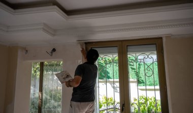 Adam duvarı yeniliyor ve boyuyor.