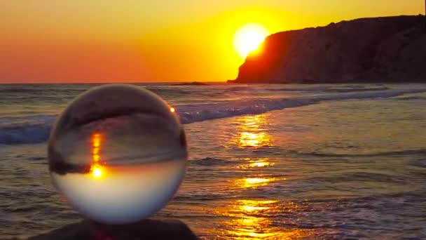 Glaskugle Står Fokus Klippe Foran Havet Med Lysbølger Ved Solnedgang – Stock-video