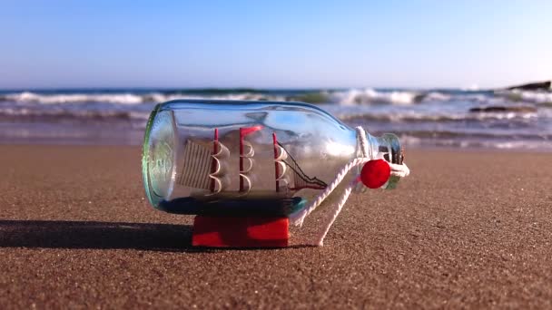 瓶の中の船は砂浜にあり ゆっくりと波に洗われます — ストック動画