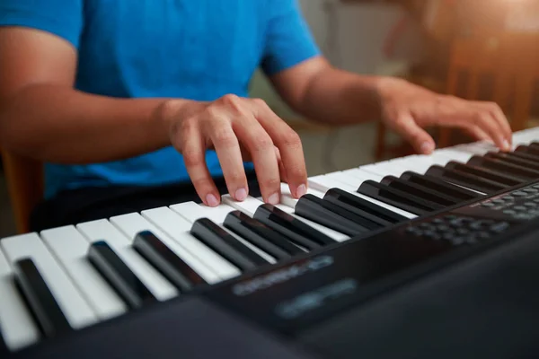 Asyalı adam evde piyano çalıyor.