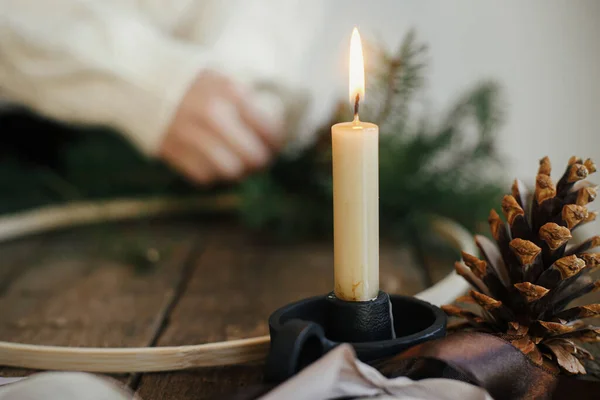 在手工制作的现代圣诞花环的背景上 有时尚的燃烧的蜡烛和松果 带有冷杉枝条 放在乡村木桌上 大气图像 圣诞节来了 寒假准备 — 图库照片