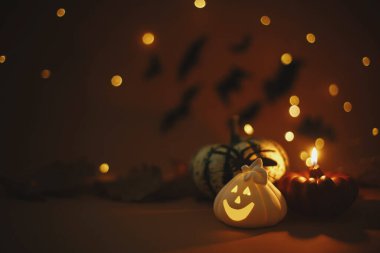 Atmosferik Cadılar Bayramı geçmişi. Balkabağı, parlayan balkabağı fener, yanan mum, koyu turuncu arka planda uçan siyah yarasalar ve sihirli ışıklar olan örümcek. Mutlu Cadılar Bayramı. Metin için boşluk