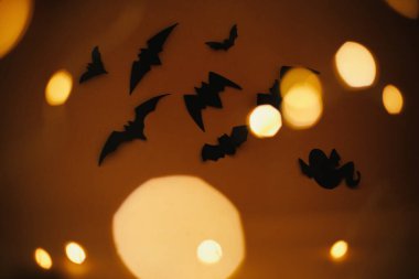 Cadılar Bayramı geçmişi. Yarasalar koyu turuncu arka planda uçan sihirli ışıklarla bokeh. Mutlu Cadılar Bayramı. Atmosfer havası. Mesaj için yeri olan tebrik kartı. Şenlikli şeytani korkunç dekorasyonlar.