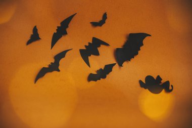 Cadılar Bayramı geçmişi. Yarasalar koyu turuncu arka planda uçan sihirli ışıklarla bokeh. Mutlu Cadılar Bayramı. Atmosfer havası. Mesaj için yeri olan tebrik kartı. Şenlikli şeytani korkunç dekorasyonlar.