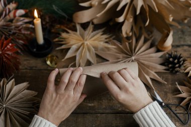 Şık Noel yıldızları yapmak. El yapımı İsveç yıldızlarının arka planında el işi kağıt katlama, iplik, mum, kırsal ahşap üzerinde makas. Şenlik dekoru yapma süreci. Tatil hazırlıkları