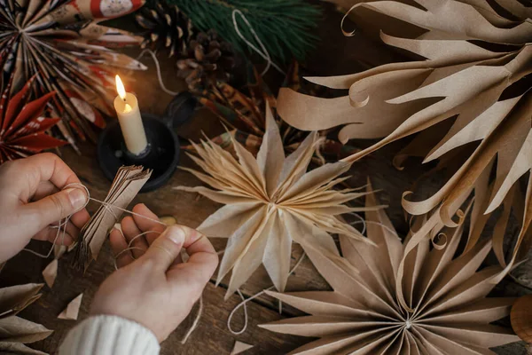 制造时尚的圣诞明星 手拿着折叠的手工纸片 背景是手工制作的瑞典星星 剪子和乡村木料 喜庆装饰的制作过程 — 图库照片