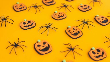 Cadılar Bayramı geçmişi. Modern balkabakları Jack o Lantern ve turuncu arka planda örümcekler. Mutlu Cadılar Bayramı şenlikleri. Sarı kağıtta Cadılar Bayramı süsleri