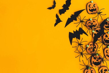 Mutlu Cadılar Bayramı. Modern balkabakları jack o fener, örümcekler, yarasalar turuncu zemin üzerinde uzanan düz metin için boşluk. Sezonun tebrik kartı. Sarı kağıtta Cadılar Bayramı süsleri