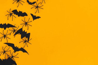 Cadılar Bayramı yatıyordu. Turuncu arka planda örümcekler ve yarasalar için metin alanı var. Mutlu Cadılar Bayramı, sezonun tebrik kartı. Cadılar Bayramı süslemeleri sarı kağıt üzerinde sınırdır. Minimalist