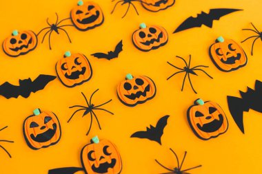 Cadılar Bayramı geçmişi. Modern balkabakları Jack o Lantern, örümcekler, turuncu arka planda yarasa yerleşimi. Mutlu Cadılar Bayramı şenlikleri. Sarı kağıtta Cadılar Bayramı süsleri