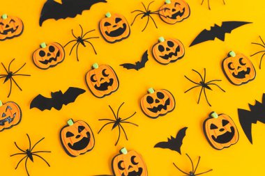 Mutlu Cadılar Bayramı. Balkabağı Jack o fener, örümcekler ve yarasalar turuncu arka planda yatıyordu. Turuncu kağıtta Cadılar Bayramı dekorasyonu. Cadılar Bayramı geçmişi. Şenlik deseni