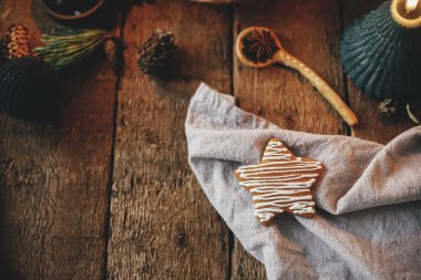 Noel yıldızı, kırsal masada mum, peçete, dekorasyon ve baharatla zencefilli kurabiye süsledi. Atmosferik karamsar görüntü. Havalı Noel kurabiyeleri yapmak için. İyi tatiller.!