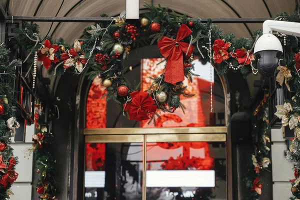 黄金の装飾と建物の入り口に赤い弓とスタイリッシュな現代のクリスマスリースとトウヒの枝 ヨーロッパの街の冬の休日のためのクリスマスの装飾 — ストック写真