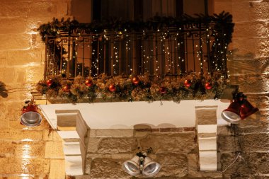 Şık Noel çanları, dallar, süsler gece vakti binanın balkonunda ışıklandırma. Atmosferik sihir zamanı. Kış tatilleri için Noel dekorasyonu. Mutlu Noeller.!