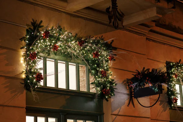 建物の窓や夜のドアに照明の装飾が施されたスタイリッシュなクリスマススプルースの枝 大気魔法の時間だ 冬の休日のためのクリスマスの装飾 — ストック写真