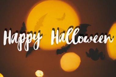 Koyu turuncu arka planda uçuşan siyah yarasalarla ilgili Cadılar Bayramı mesajınız kutlu olsun. Sezonun tebrik kartı. El yazısıyla mutlu cadılar bayramı mesajı. Şaka mı şeker mi?