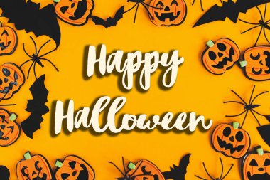 Balkabaklarının, fenerlerin, örümceklerin, yarasaların, turuncu arka planda yattıkları Cadılar Bayramı tabelasının kutlu olsun. Sezonun tebrik kartı. El yazısıyla mutlu cadılar bayramı mesajı. Şaka mı şeker mi?