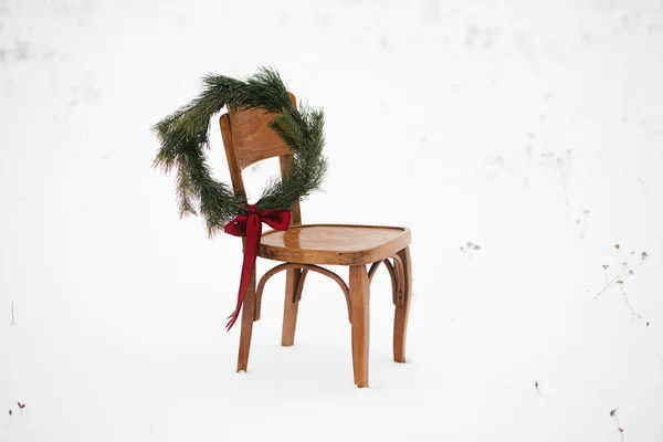 크리스마스 눈내리는 들판의 의자에 크리스마스 화환을 걸었습니다 시골에서의 문자를 의자에 — 스톡 사진